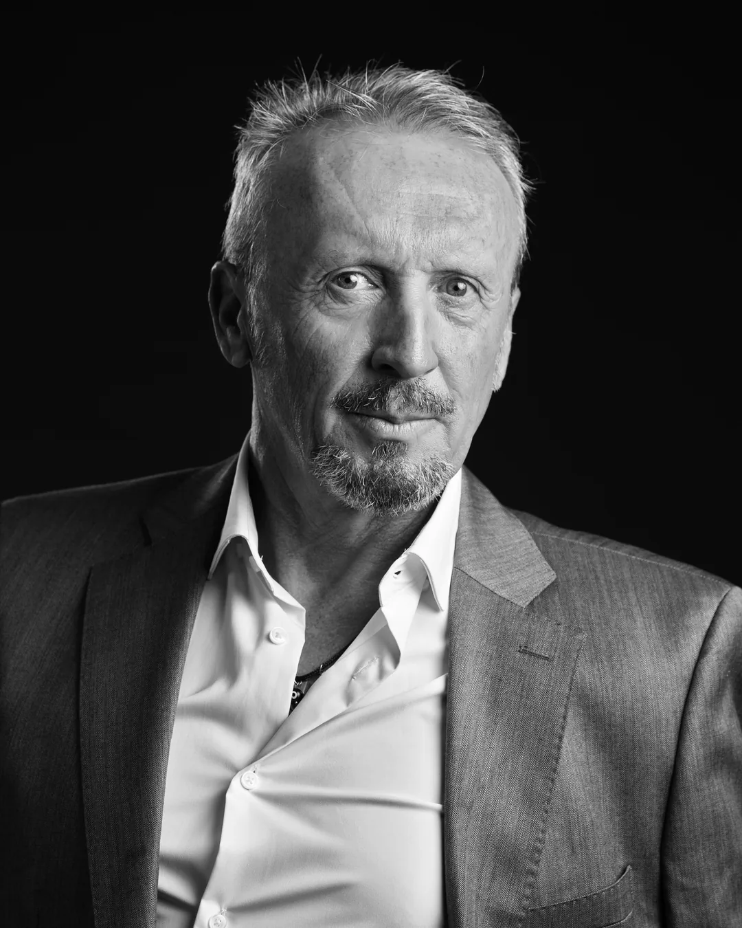 Retrato en blanco y negro de Paco Gumiel con americana y camisa blanca, mirando a cámara