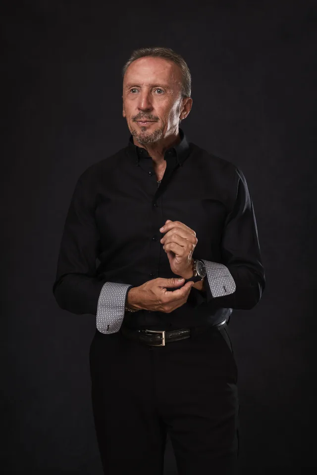 Paco Gumiel con camisa negra, ajustándose el puño, sobre fondo negro